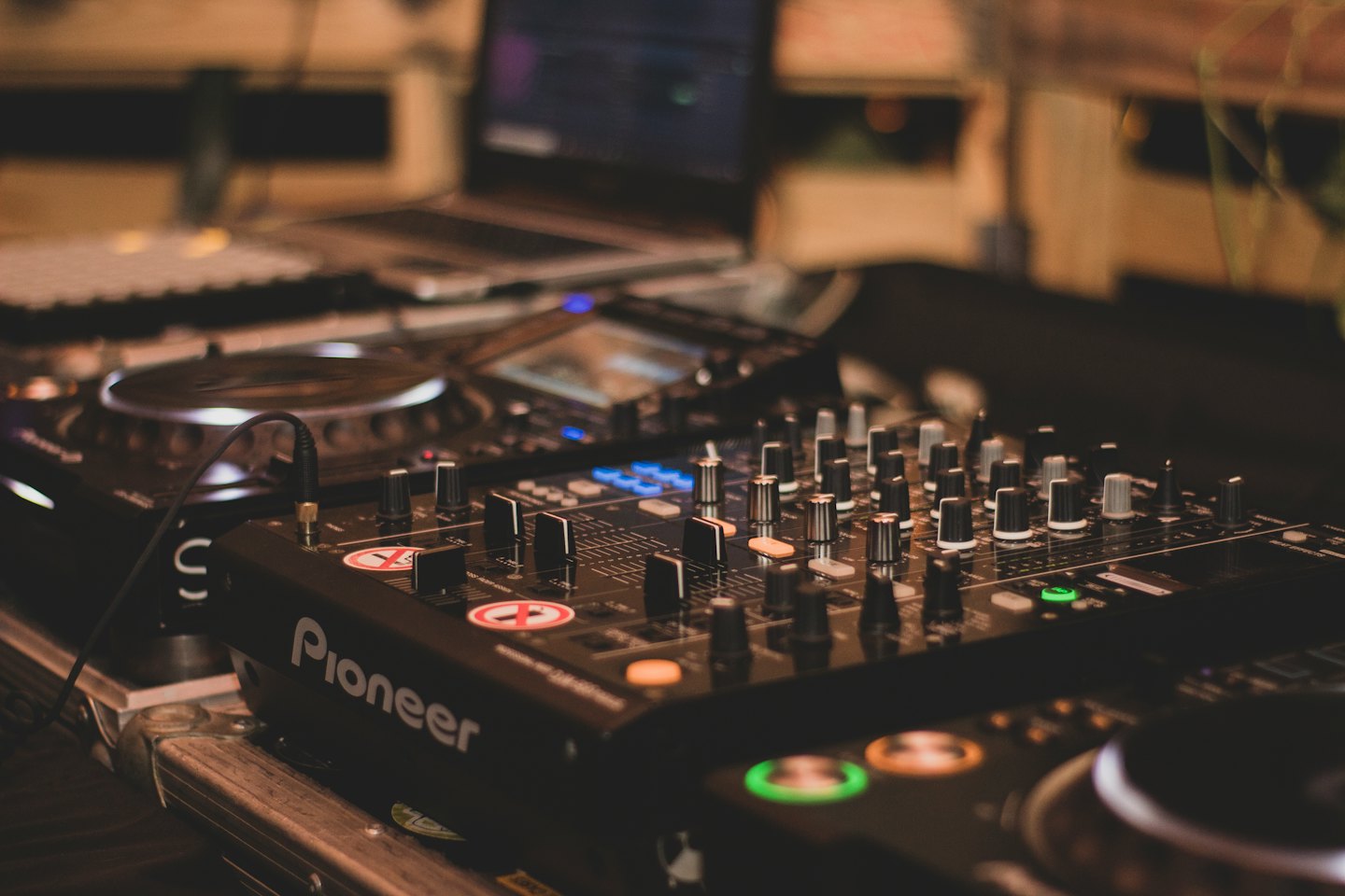DJ mixer and turntables with a laptop on a table.