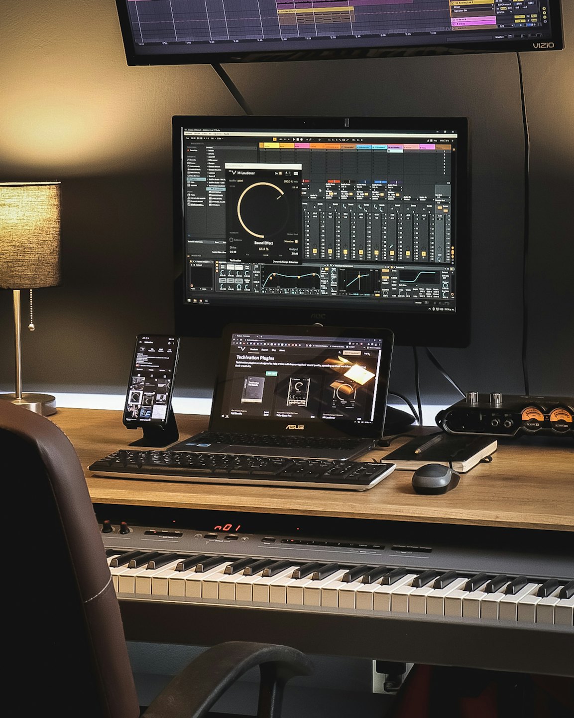 Music production workstation with multiple monitors and keyboard.