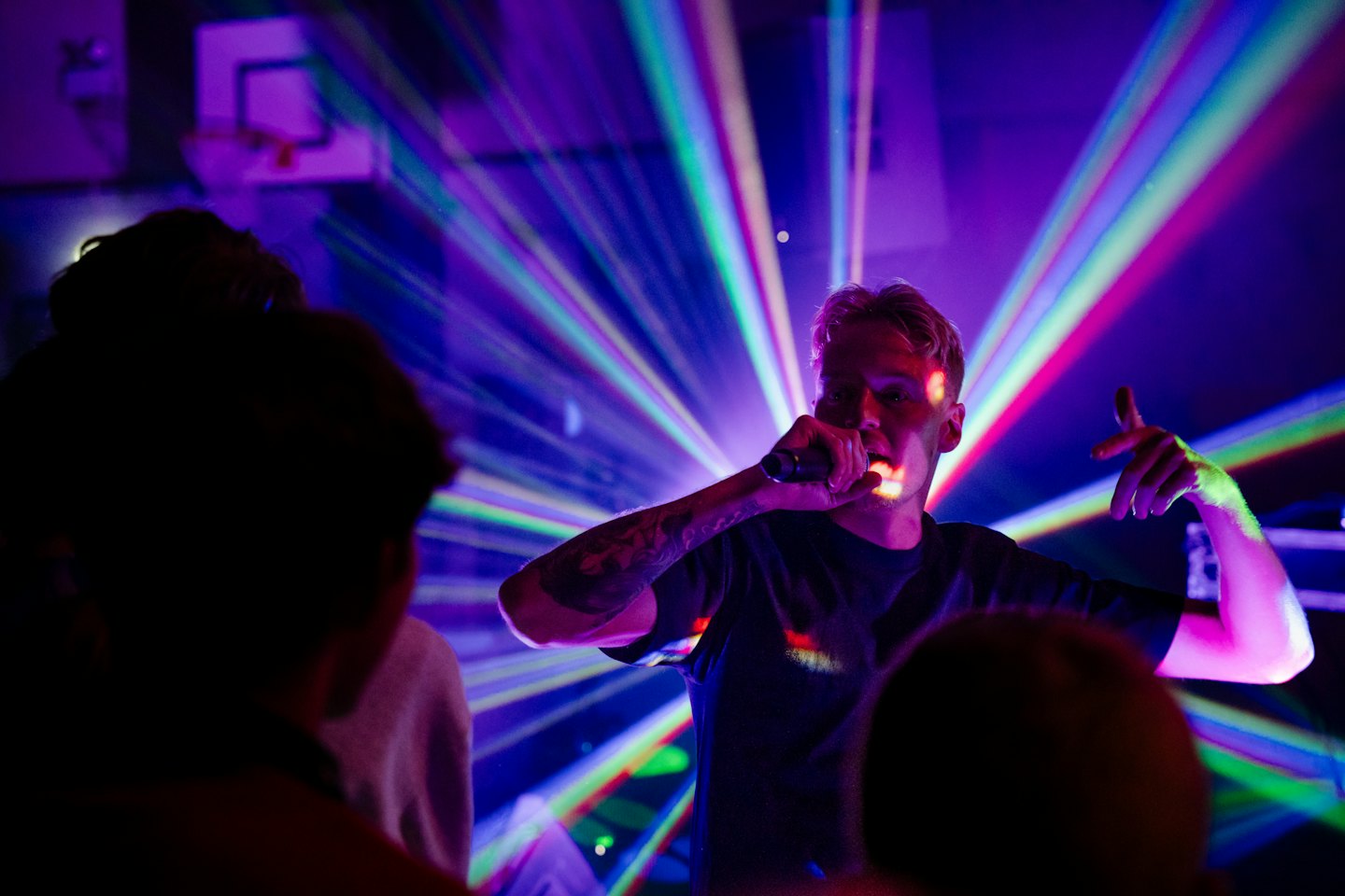 Man singing into microphone on a stage with colorful lights.
