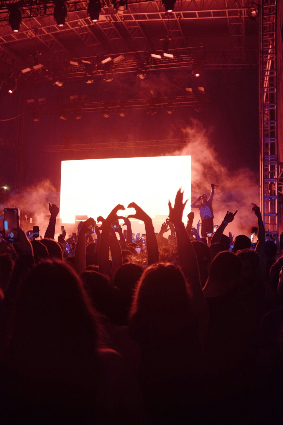 Concertgoers raise their hands while watching a performer on stage.