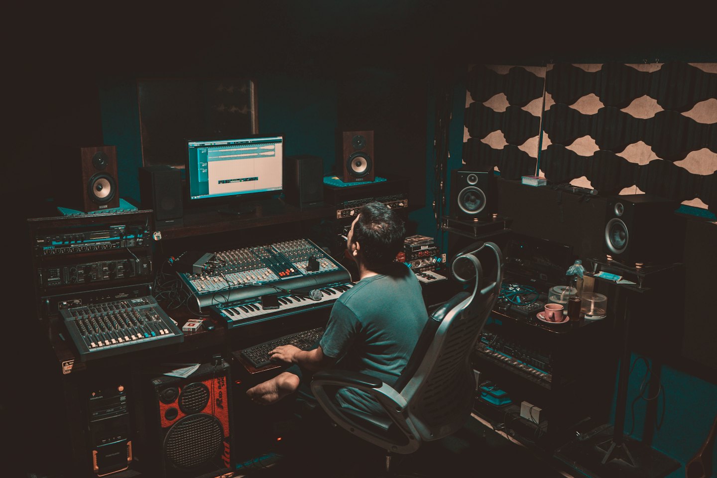 Man working at sound mixing console and computer monitors.