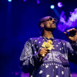 Snoop Dogg exhales smoke while holding a gold microphone during a concert in Sydney.