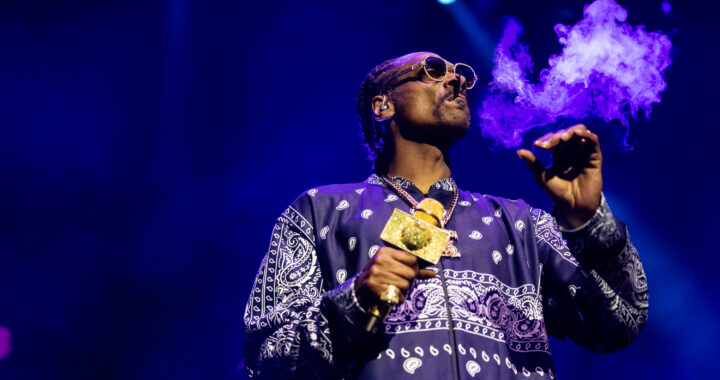 Snoop Dogg exhales smoke while holding a gold microphone during a concert in Sydney.