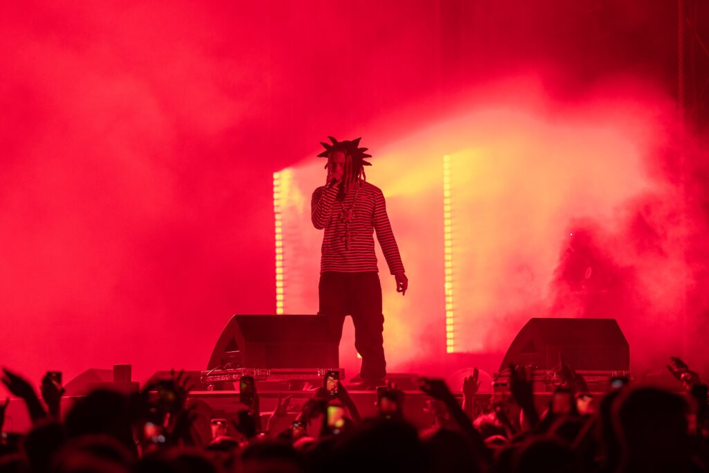 Trippie Redd performs onstage amid red lighting and smoke at Clout Festival 2024.