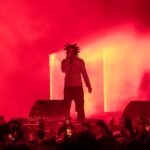 Trippie Redd performs onstage amid red lighting and smoke at Clout Festival 2024.