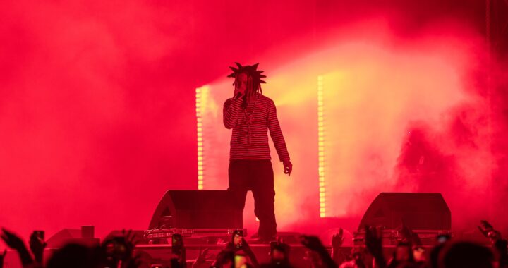 Trippie Redd performs onstage amid red lighting and smoke at Clout Festival 2024.